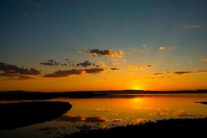 puesta de sol antecedentes foto. rayos de sol y parcialmente nublado cielo terminado el lago foto