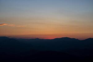 Silhouette of the hills at sunset with hazy sky. photo