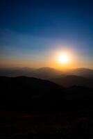 puesta de sol terminado el colinas y silueta de el sierras. foto