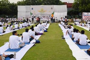 nuevo Delhi, India, junio 21, 2023 - grupo yoga ejercicio sesión para personas a yamuna Deportes complejo en Delhi en internacional yoga día, grande grupo de adultos asistiendo yoga clase en Grillo estadio foto