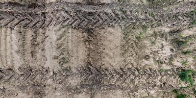 view from above on texture of wet muddy road with tractor tire tracks in countryside photo