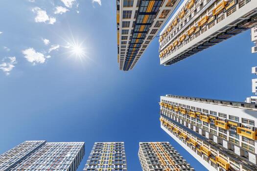 ver desde abajo dentro azul cielo con nubes de grande moderno rascacielos residencial complejo foto