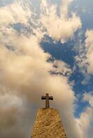 silhouette of stone grave cross against the background of a blue evening sky with clouds photo