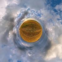 simple tiny planet without buildings in blue sky with beautiful clouds. Transformation of spherical panorama 360 degrees. Spherical abstract aerial view. Curvature of space. photo