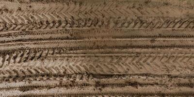 view from above on texture of wet muddy road with puddle and tractor tire tracks in countryside photo