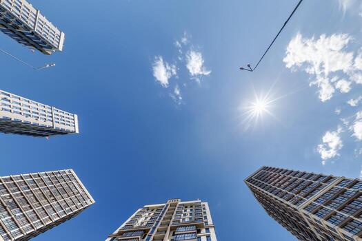 ver desde abajo dentro azul cielo con nubes de grande moderno rascacielos residencial complejo foto