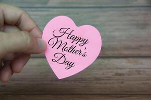 Hand holding Happy Mother's Day text on pink paper. Mother's day concept photo