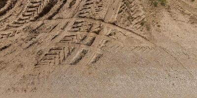 view from above on texture of wet muddy road with puddle and tractor tire tracks in countryside photo