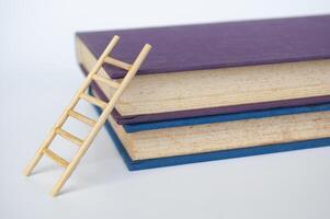 Toy wooden ladder next to books with white background. Learning concept photo