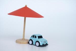 Red toy umbrella and blue toy car on white background photo