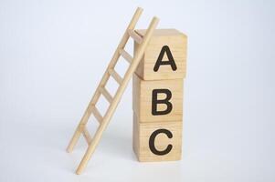 a B C texto en de madera cubitos con escalera en blanco antecedentes. aprendizaje concepto foto