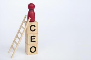 Red doll figure on top of wooden cubes with CEO text. Leadership and success concept photo