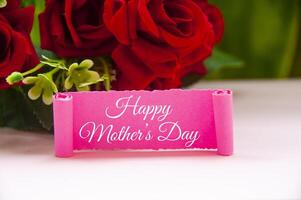 Happy mother's day text on pink paper with roses background. Mother's day concept. photo