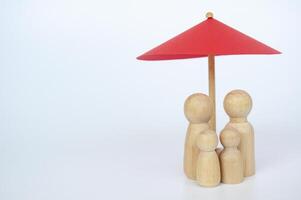 Red umbrella and wooden family doll figures with customizable space for text. Insurance concept photo