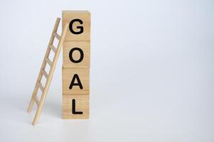 Goal text on wooden cubes with ladder on white background photo