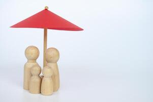 Red umbrella and wooden family doll figures with customizable space for text. Insurance concept photo