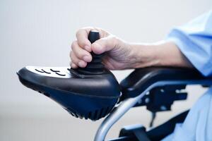 Asian elderly disability woman patient use joystick electric wheelchair in hospital. photo