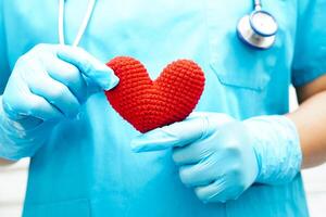 Asian woman doctor holding red heart for health in hospital. photo