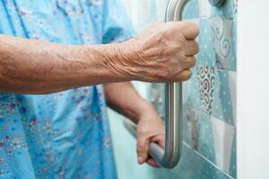 Asian elderly old woman patient use toilet support rail in bathroom, handrail safety grab bar, security in nursing hospital. photo