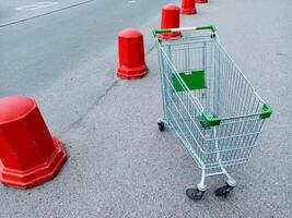 Empty shopping cart on the road with red traffic cones in the background photo