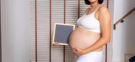 grande embarazada mujer con letra tablero foto
