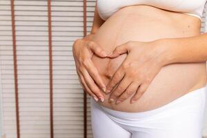 Portrait of a pregnant woman touching her big belly close up, mother, pregnancy, people and expectation. Woman holding big pregnant stomach photo