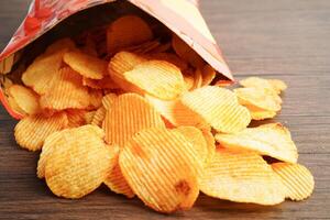 papas fritas en bolsa abierta, delicioso condimento de barbacoa picante para crips, refrigerio frito en rodajas finas comida rápida. foto