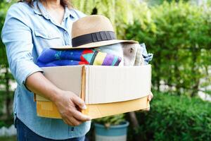 Volunteer collect cloth and hat in cardboard box to donate. photo