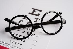 Glasses on eye exam chart to test eyesight accuracy of reading. photo