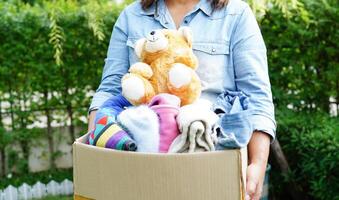 Volunteer collect cloth and doll in cardboard box to donate. photo