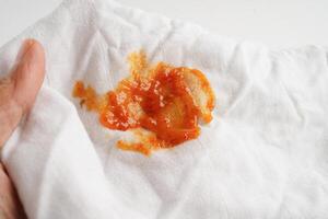 Dirty tomato sauce stain or ketchup on cloth to wash with washing powder, cleaning housework concept. photo