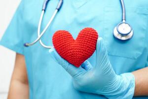 Asian woman doctor holding red heart for health in hospital. photo