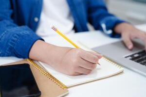 Asian teenage student write homework with laptop computer, learning university education concept. photo