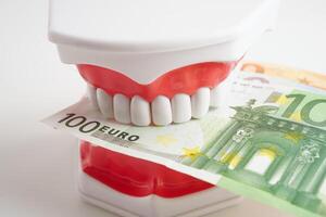 Treatment dental care cost, dental expense or fee, Euro banknote money with teeth model. photo