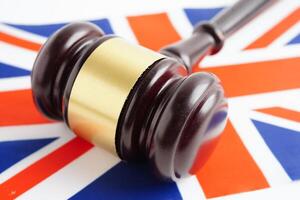 United Kingdom, Legal, justice and agreement, wooden court gavel on flag. photo