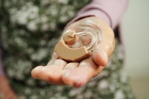 Asian senior woman patient using hearing aid in ear to reduce hearing loss problem. photo