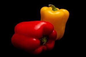 Red and yellow pepper in black background photo