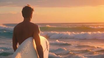 een Mens is staand Aan een strand, Holding een surfboard onder zijn arm, klaar naar raken de golven. video