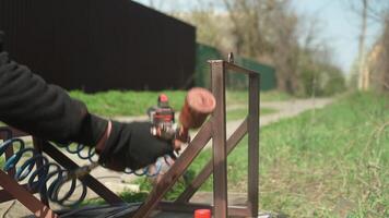 Craftsman paints a metal structure using a spray gun. Worker applies paint with paint sprayer and compressor video