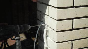 Baumeister Bohrer ein Loch im das Mauer mit ein Hammer bohren. Nahansicht von Hammer bohren Perforator Herstellung Loch video