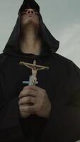 religioso monje reza con un crucifijo de Jesús en su mano arrodillado en el arena video