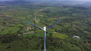 vento turbina com lâminas dentro verde rural área dentro Portugal em ensolarado dia. aéreo visualizar. alternativo renovável energia. zangão movimentos avançar, inclinar baixa video