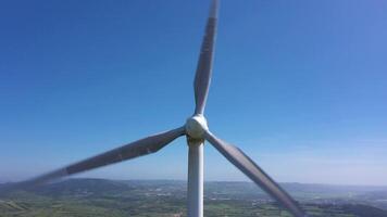 Wind Turbine mit Klingen im Grün ländlich Bereich im Portugal auf sonnig Tag. Antenne Sicht. Alternative verlängerbar Energie. Drohne bewegt sich nach oben, Neigung Nieder video