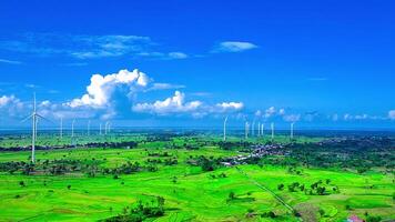 Aerial view of a wind turbine farm with rice paddies and a beautiful sky video