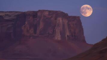 a lua pares sobre a Beira do a áspero mesa fundição a sobrenatural brilho sobre a deserto panorama abaixo. 2d plano desenho animado video