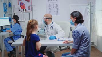 radioloog met bescherming masker vragen voor kind röntgenstraal en controle het. arts specialist in geneeskunde het verstrekken van Gezondheid zorg Diensten overleg behandeling in ziekenhuis kabinet gedurende covid-19 video