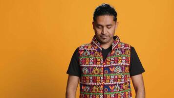 Portrait of jolly indian man with colorful garment smiling, looking pleased, isolated over studio background. Joyous person in traditional attire feeling carefree, camera A video