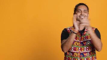 Joyful indian man happily clapping hands, ecstatic about accomplishments. Excited person reacting to good news, cheering, applauding, isolated over studio background, camera A video