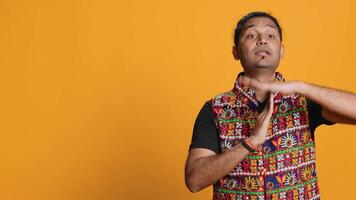 Portrait of assertive indian man asking for timeout, doing hand gestures, feeling fatigued. Firm person doing vehement pause sign gesturing, wishing for break, studio background, camera A video