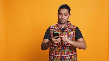 Happy man playing videogames on smartphone, celebrating after defeating foes, doing clenching hand gesture. Player swiping phone screen, thrilled about winning game, studio background, camera B video